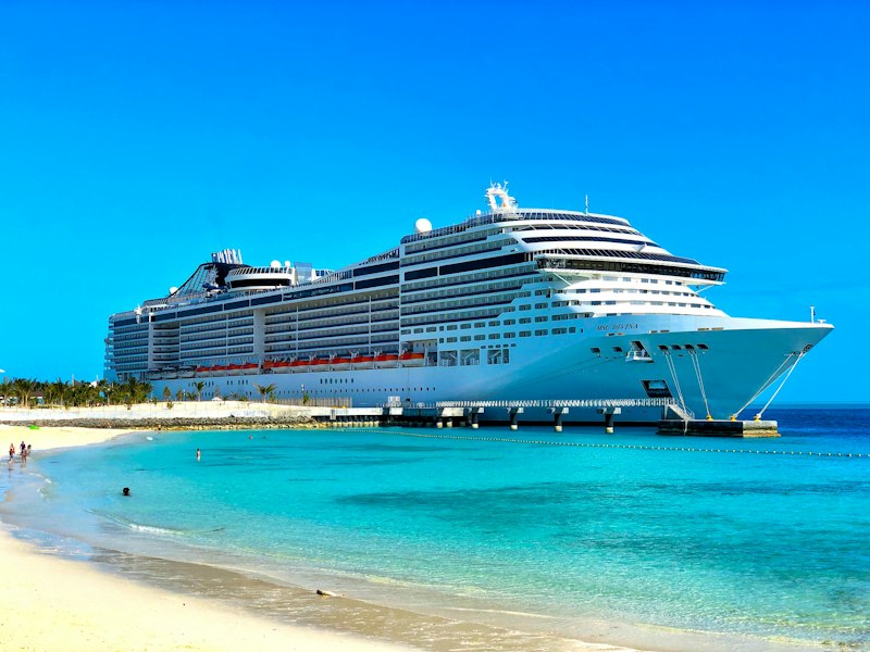 Luxury cruise ship docked by a white sand beach